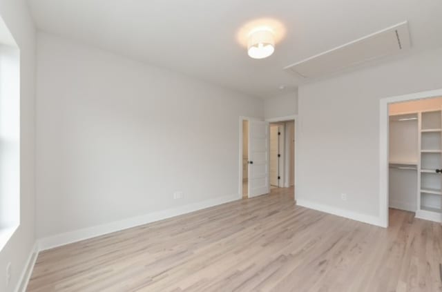 unfurnished bedroom with a closet, a walk in closet, and light hardwood / wood-style flooring