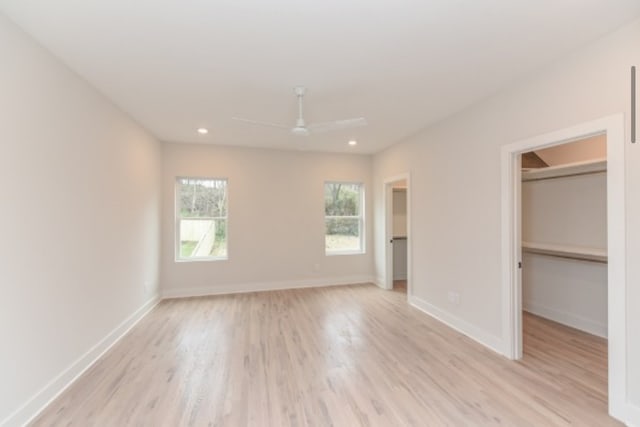 unfurnished bedroom featuring a spacious closet, ceiling fan, a closet, and light hardwood / wood-style floors