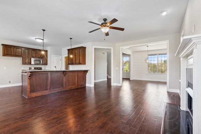 kitchen with appliances with stainless steel finishes, dark hardwood / wood-style flooring, kitchen peninsula, and a kitchen breakfast bar