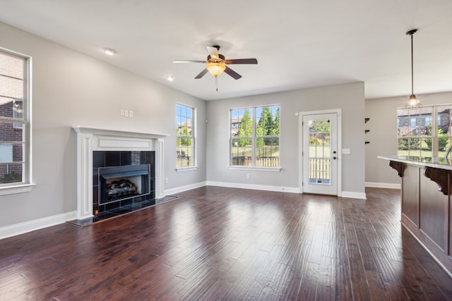 unfurnished living room featuring dark wood-type flooring, a tile fireplace, and ceiling fan