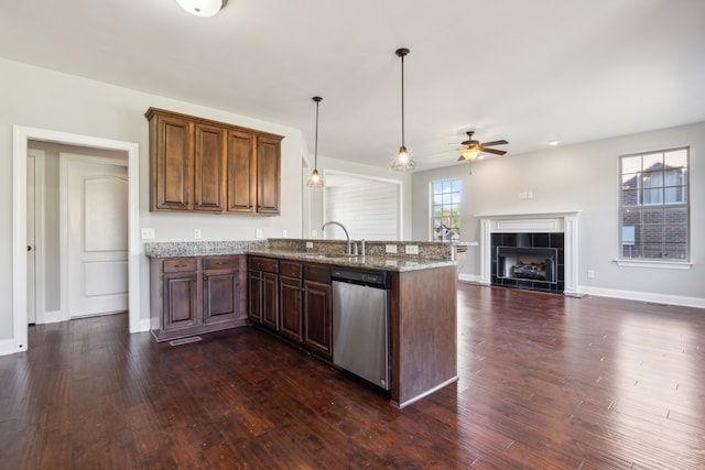 kitchen featuring dishwasher, kitchen peninsula, decorative light fixtures, a fireplace, and dark hardwood / wood-style flooring