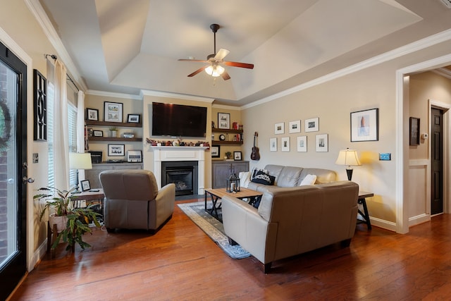 living room with ceiling fan, a raised ceiling, crown molding, and hardwood / wood-style floors