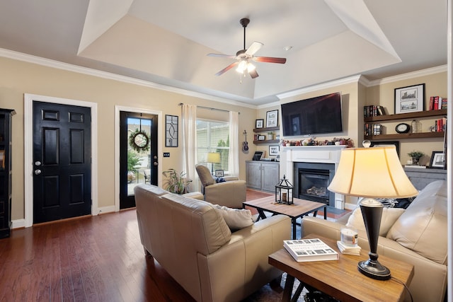 living room with ceiling fan, a raised ceiling, crown molding, and dark hardwood / wood-style flooring