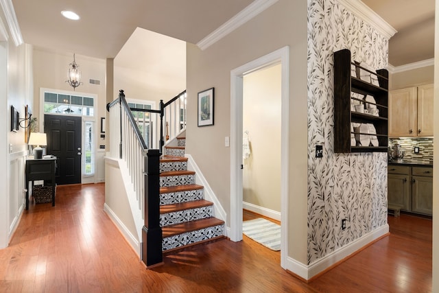 foyer featuring hardwood / wood-style flooring, crown molding, and a notable chandelier