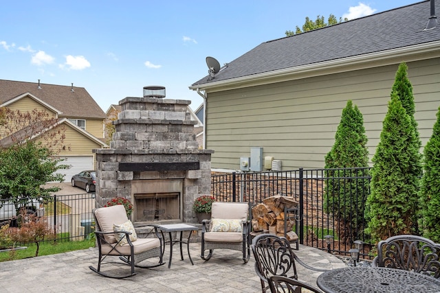 view of patio / terrace with a garage and an outdoor stone fireplace