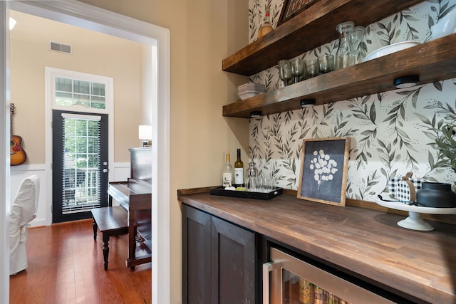 bar with dark wood-type flooring, wooden counters, and wine cooler