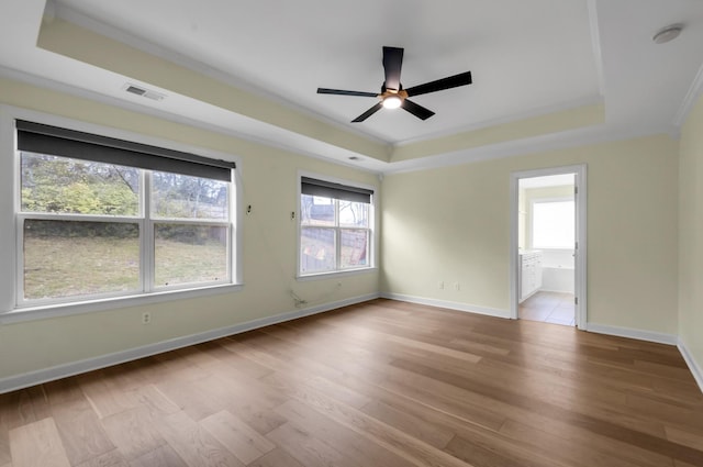 unfurnished room with a tray ceiling, crown molding, and light hardwood / wood-style flooring