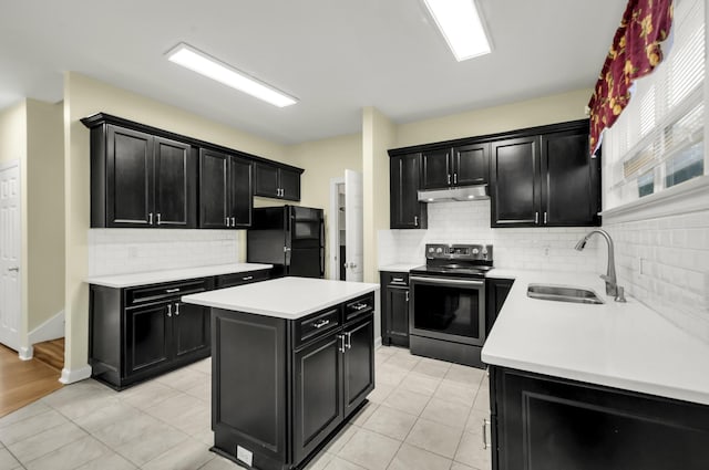 kitchen featuring stainless steel electric range oven, a center island, sink, black fridge, and backsplash