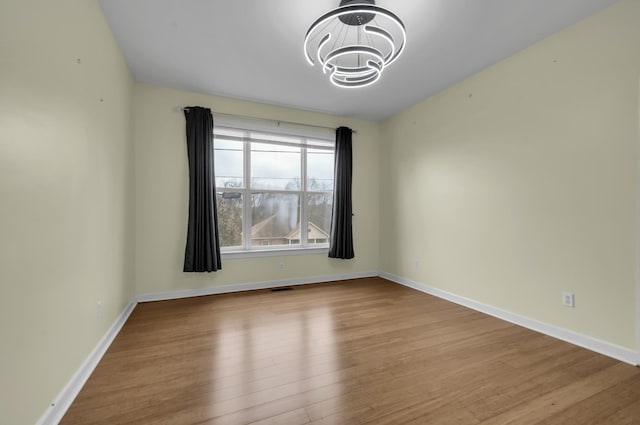 empty room featuring a chandelier and light hardwood / wood-style flooring