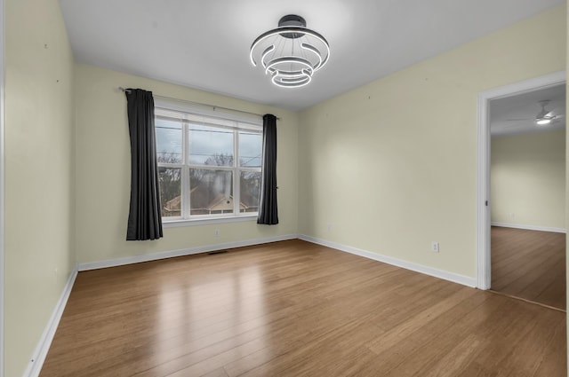 unfurnished room featuring light hardwood / wood-style flooring and ceiling fan with notable chandelier