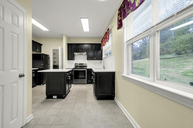 kitchen featuring electric range, a center island, sink, black fridge, and light tile patterned floors