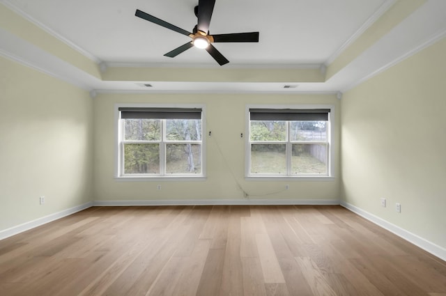 spare room featuring light wood-type flooring, a tray ceiling, ceiling fan, and ornamental molding