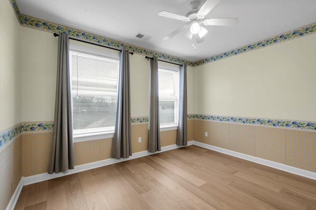 empty room with light wood-type flooring, tile walls, and ceiling fan