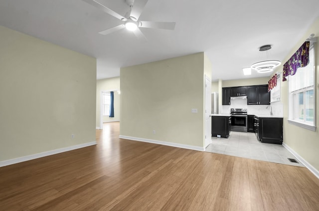 unfurnished living room featuring light hardwood / wood-style flooring, ceiling fan, and sink