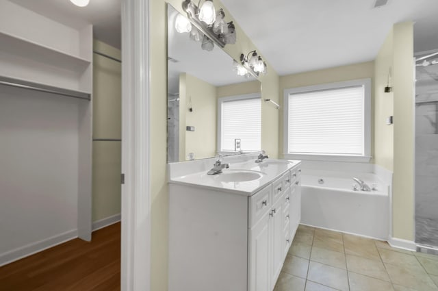 bathroom with tile patterned flooring, a washtub, and vanity