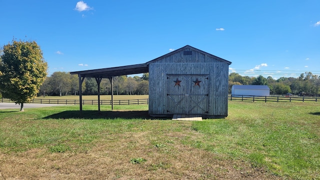 view of outbuilding featuring a rural view and a lawn