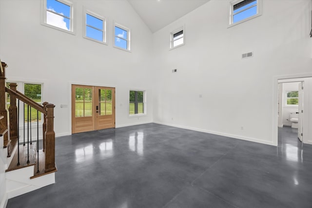 unfurnished living room with french doors and high vaulted ceiling