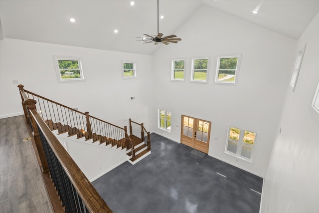 stairway with wood-type flooring, high vaulted ceiling, and ceiling fan