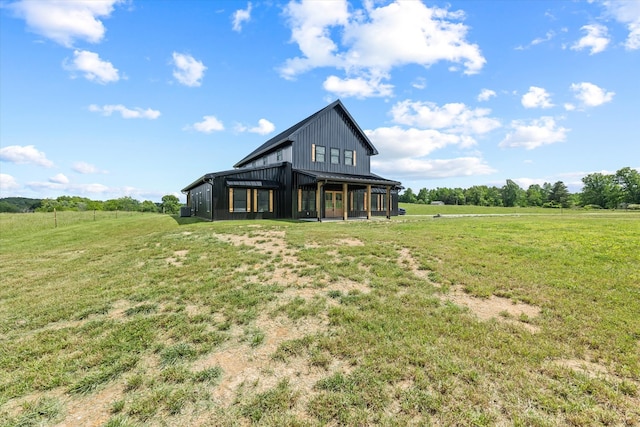 rear view of house featuring a rural view and a lawn