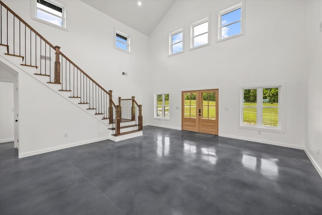 unfurnished living room featuring a high ceiling and french doors