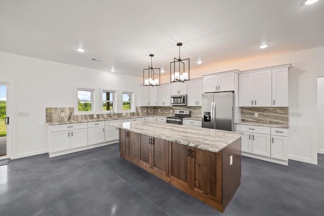 kitchen with tasteful backsplash, a kitchen island, stainless steel appliances, hanging light fixtures, and white cabinets