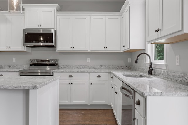 kitchen with sink, light stone counters, dark hardwood / wood-style floors, white cabinets, and appliances with stainless steel finishes