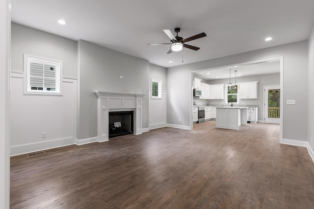 unfurnished living room featuring ceiling fan, hardwood / wood-style flooring, and sink