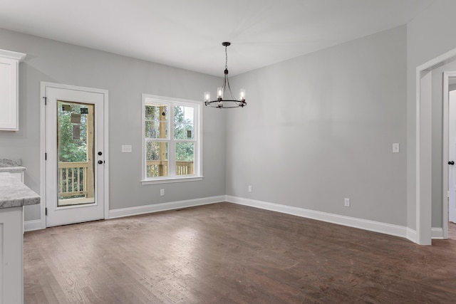 unfurnished dining area featuring a chandelier and dark hardwood / wood-style flooring