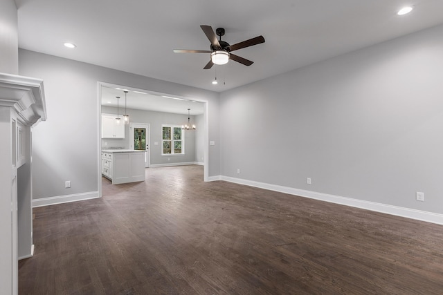 unfurnished living room with ceiling fan with notable chandelier and dark hardwood / wood-style floors