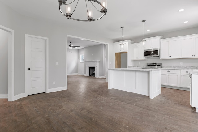 kitchen with pendant lighting, stainless steel appliances, light stone countertops, and white cabinetry