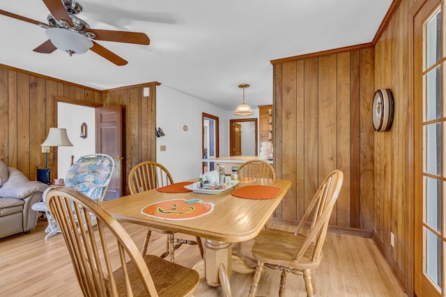 dining room featuring ceiling fan, wood walls, and light hardwood / wood-style floors