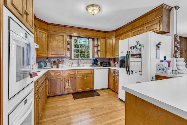 kitchen with light wood-type flooring, white appliances, and sink