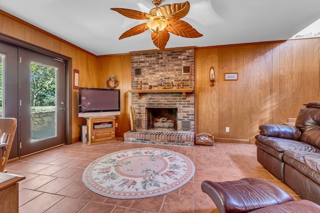 living room featuring ornamental molding, a brick fireplace, ceiling fan, and wood walls