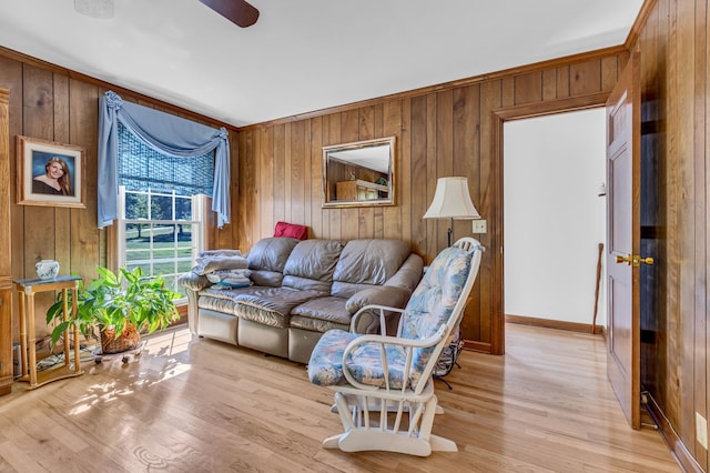 living room featuring ceiling fan, wood walls, and light hardwood / wood-style floors