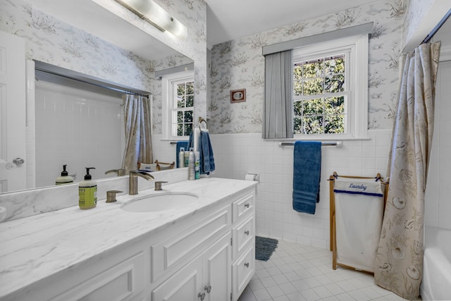 bathroom featuring shower / bath combo with shower curtain, tile patterned floors, vanity, and tile walls