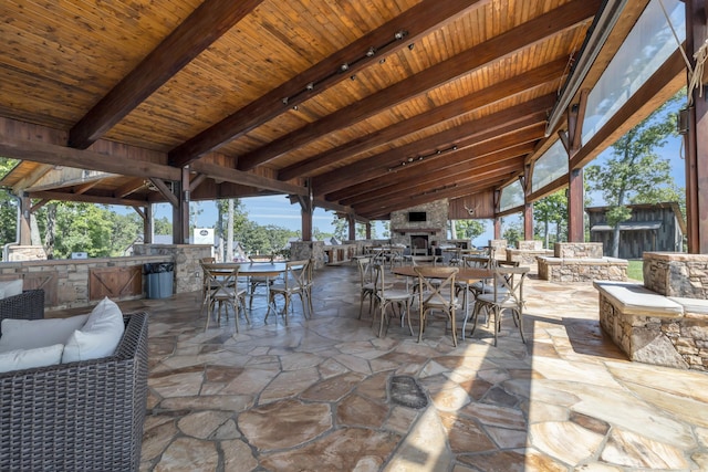 view of patio / terrace with a bar, an outdoor kitchen, and an outdoor living space with a fireplace