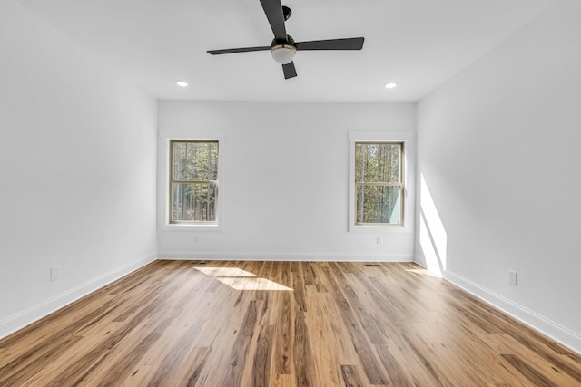 empty room with ceiling fan, light hardwood / wood-style floors, and a healthy amount of sunlight