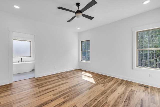 unfurnished bedroom with ceiling fan, light hardwood / wood-style flooring, ensuite bathroom, and multiple windows