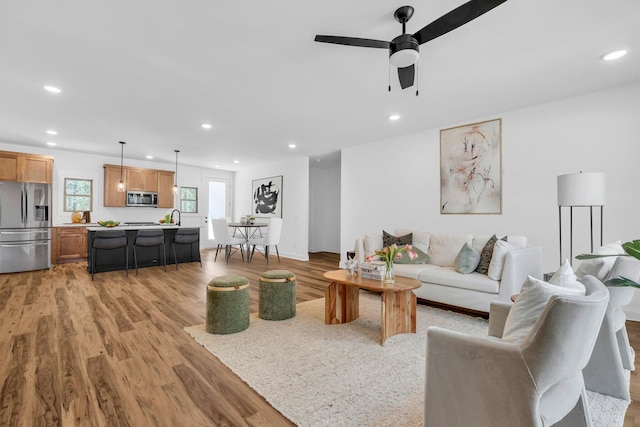 living room with ceiling fan, sink, and light hardwood / wood-style floors