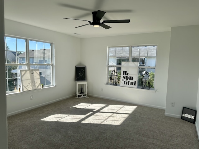 empty room with ceiling fan and dark carpet