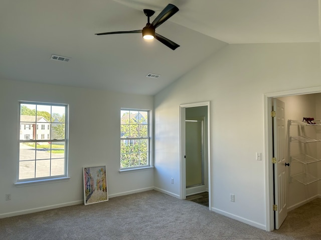 unfurnished bedroom with a spacious closet, ceiling fan, vaulted ceiling, and carpet floors