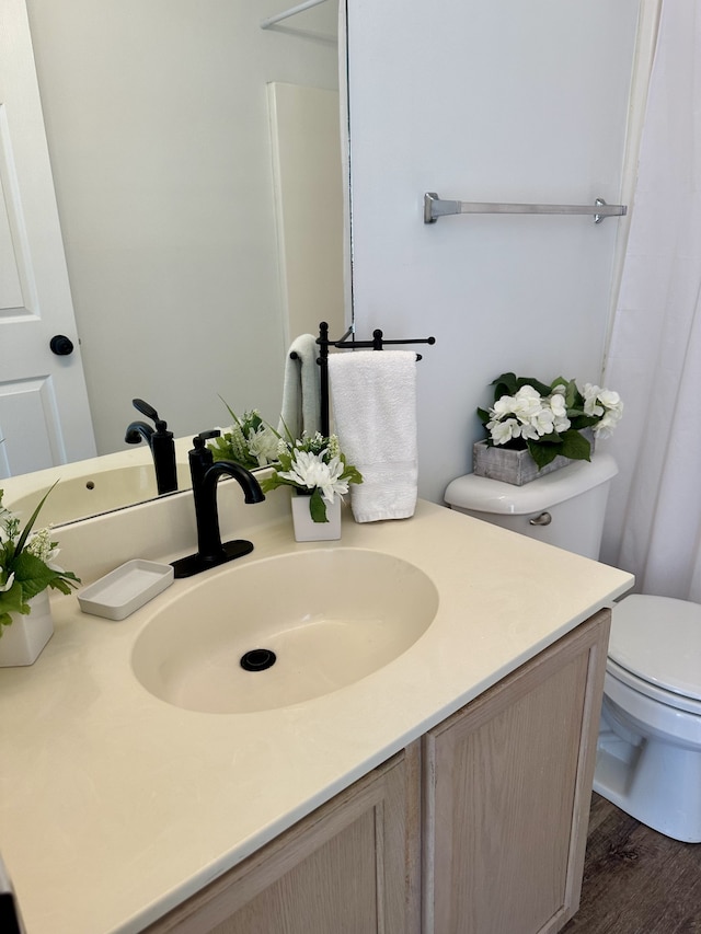 bathroom featuring wood-type flooring, toilet, and vanity