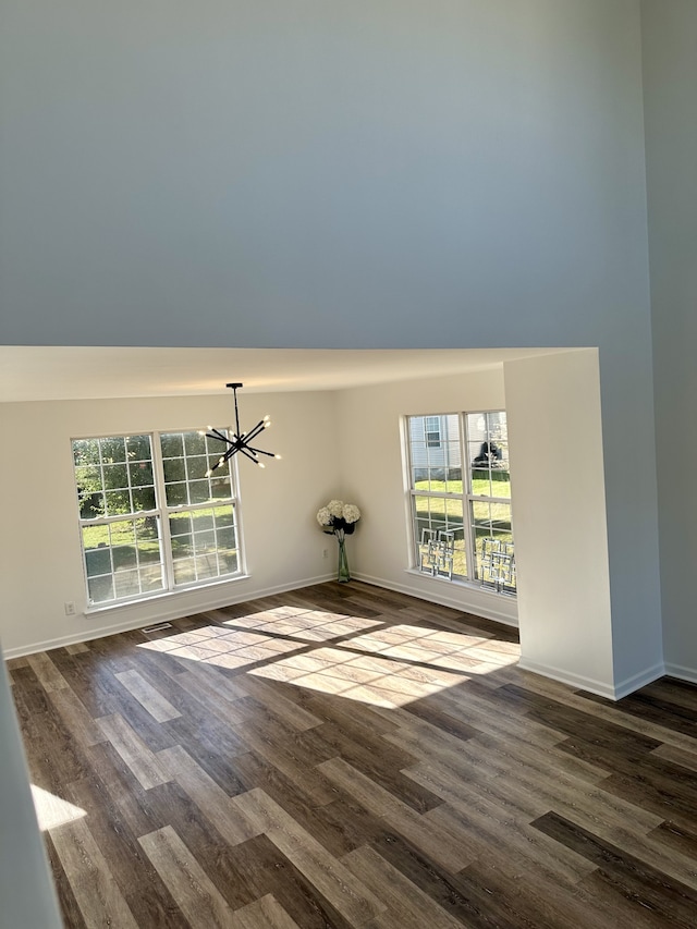 empty room with a chandelier and dark hardwood / wood-style flooring