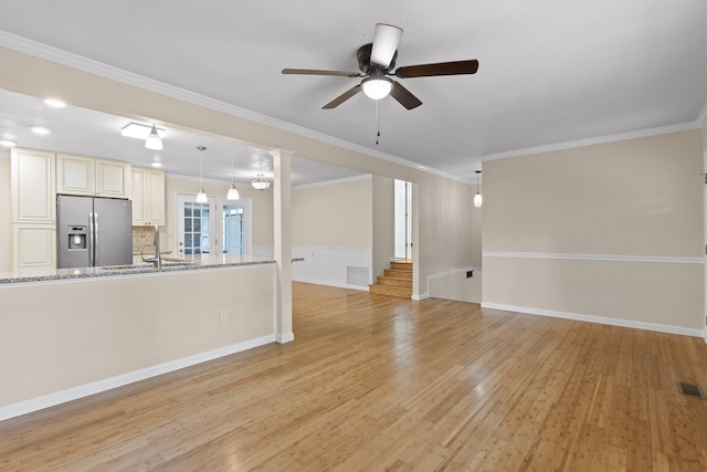 unfurnished living room featuring crown molding, light hardwood / wood-style flooring, ornate columns, and ceiling fan