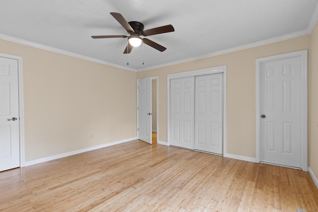 unfurnished bedroom featuring crown molding, two closets, a textured ceiling, light hardwood / wood-style floors, and ceiling fan