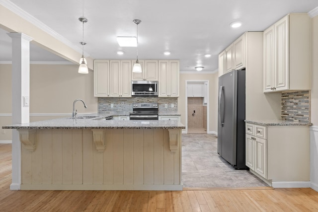 kitchen featuring kitchen peninsula, stainless steel appliances, decorative light fixtures, light wood-type flooring, and light stone counters