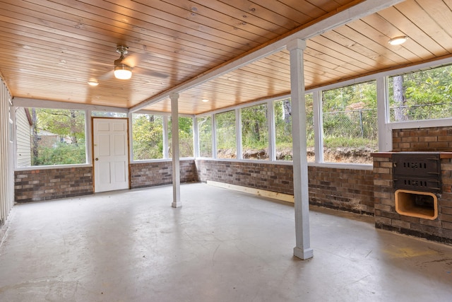 unfurnished sunroom featuring ceiling fan, wooden ceiling, and a wealth of natural light