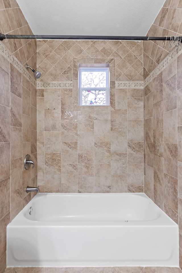 bathroom with tiled shower / bath and a textured ceiling