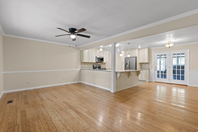 unfurnished living room featuring light hardwood / wood-style floors, crown molding, sink, and ceiling fan