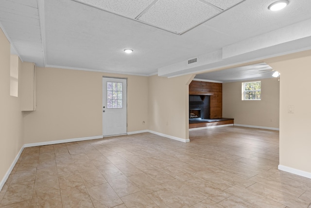 interior space featuring a wealth of natural light, ornamental molding, and a fireplace